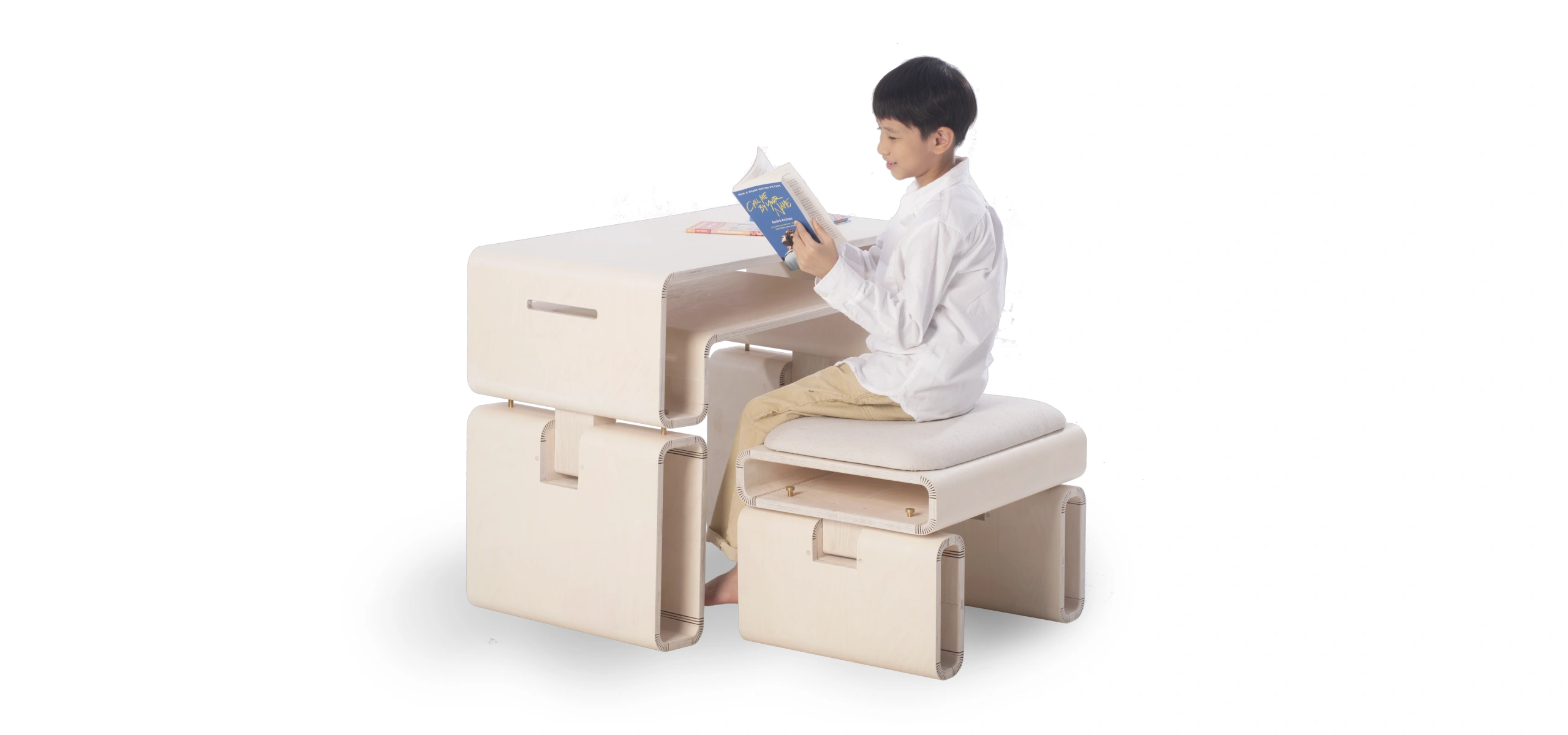 A young boy sits on The Accompanying Growth Furniture, illustrating a practical usage scenario and highlighting the furniture's adaptability.