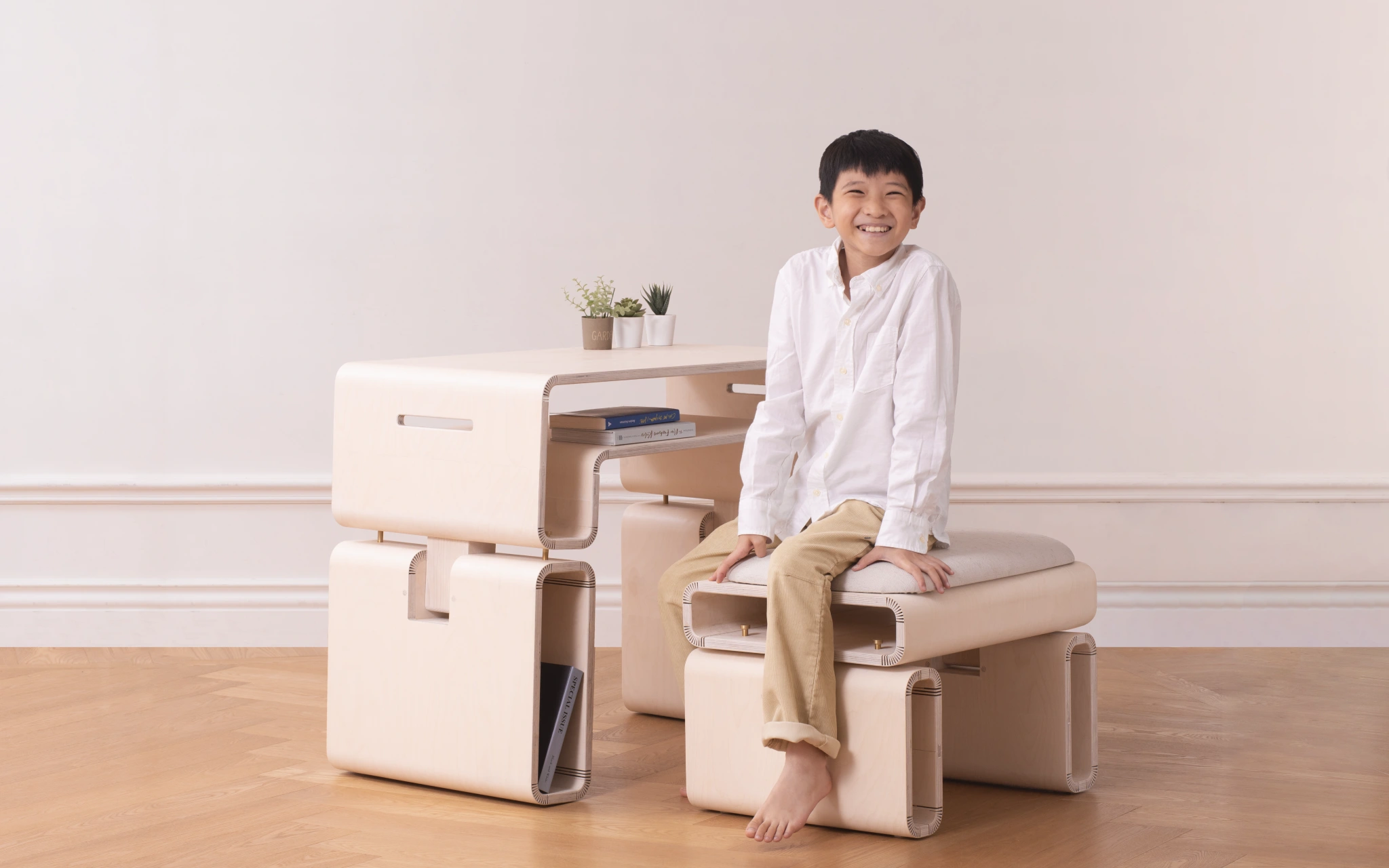 A young boy sits on The Accompanying Growth Furniture, illustrating a practical usage scenario and highlighting the furniture's adaptability.